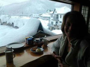 A room with a view of a snowy village through a window. - Alpine Villa Nozawa (Nozawaonsen)