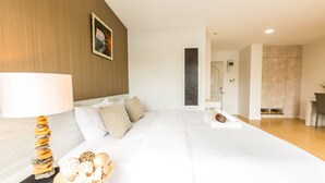 A modern hotel room with a neatly made bed, a decorative lamp, and a fruit bowl on the side table. - Baron Residence Bangkok (Bangkok)