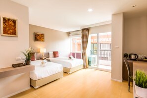 A hotel room with two beds, a desk, a chair, and a balcony with a view of the street. - Baron Residence Bangkok (Bangkok)