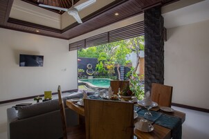 Comedor con vista a una piscina y abundante vegetación.