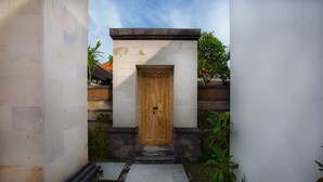 A traditional wooden door with a decorative surround, set within a stone and concrete structure.