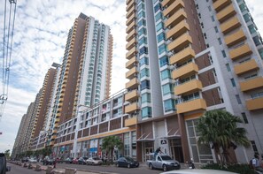 Un moderno edificio de gran altura con varios balcones y una zona comercial en la planta baja.