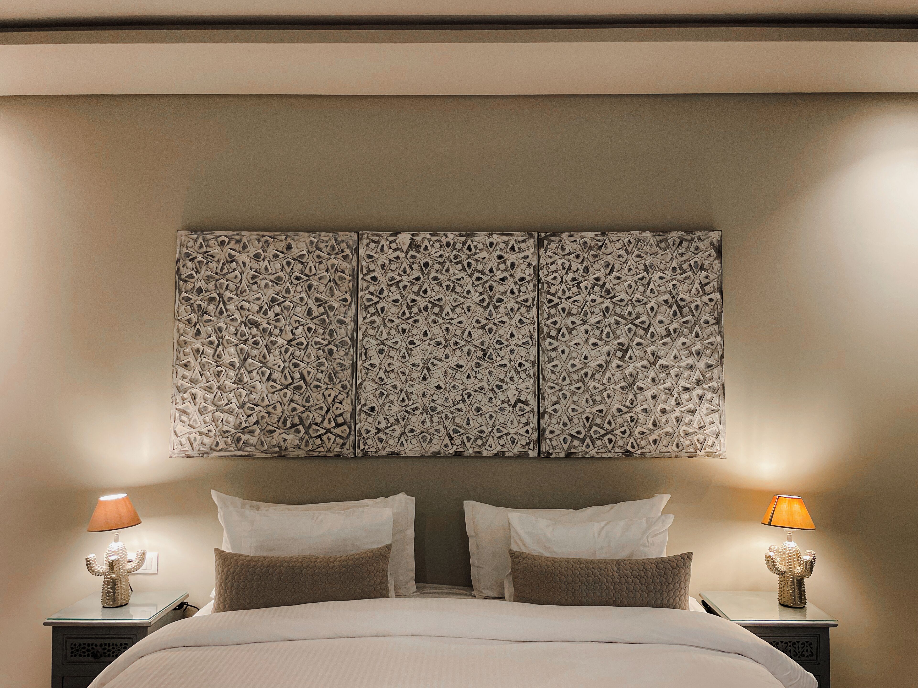 Une chambre d’hôtel avec un lit, deux tables de chevet et une tête de lit fixée au mur.