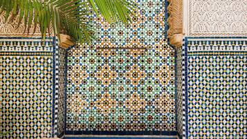 A tiled wall with geometric patterns, a bench, and a palm tree.