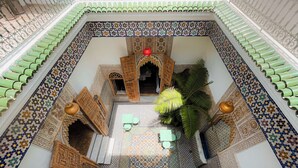 A courtyard with a tiled floor, a central seating area with chairs, and a decorative archway. - Riad Zyo (Rabat)