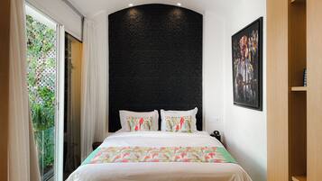 Un dormitorio con cama, pared negra texturizada, ventana con cortinas y un cuadro en la pared.