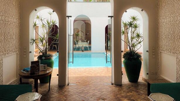 An indoor pool area with a view of the outside, surrounded by arches and potted plants. - Riad Zyo (Rabat)