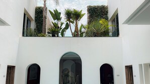 A pool area with a table and chairs, surrounded by arched doorways and a white building facade. - Riad Zyo (Rabat)