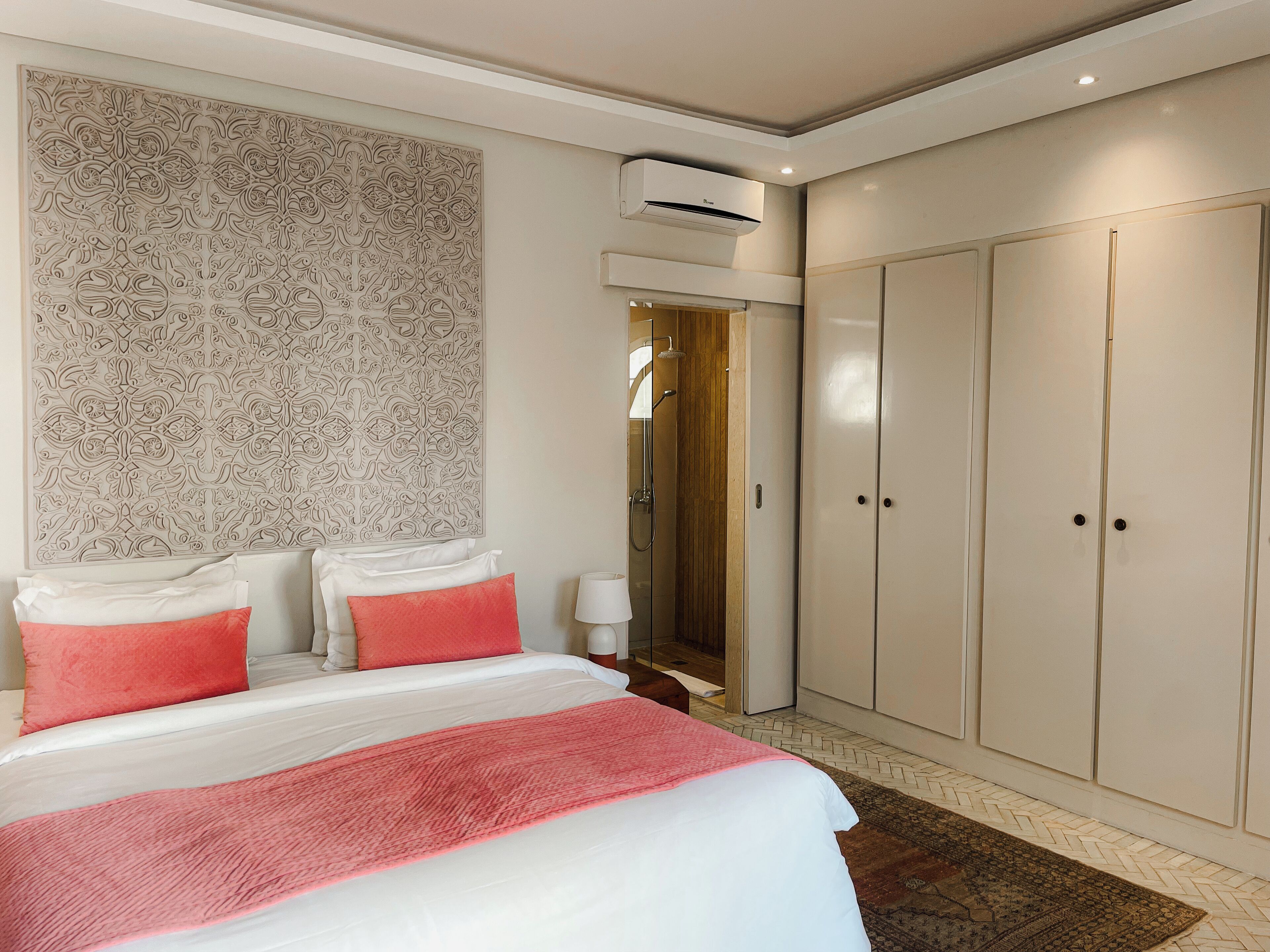 Un dormitorio con cama, armario, ducha y un panel decorativo en la pared.