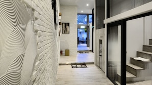 A modern interior with a brick wall, a staircase, and a view into another room. - Happy House B&B, Juifan (New Taipei City)