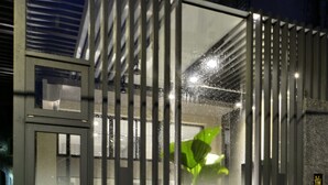 A gated entrance with a metal fence, a glass door, and a potted plant inside. - Happy House B&B, Juifan (New Taipei City)