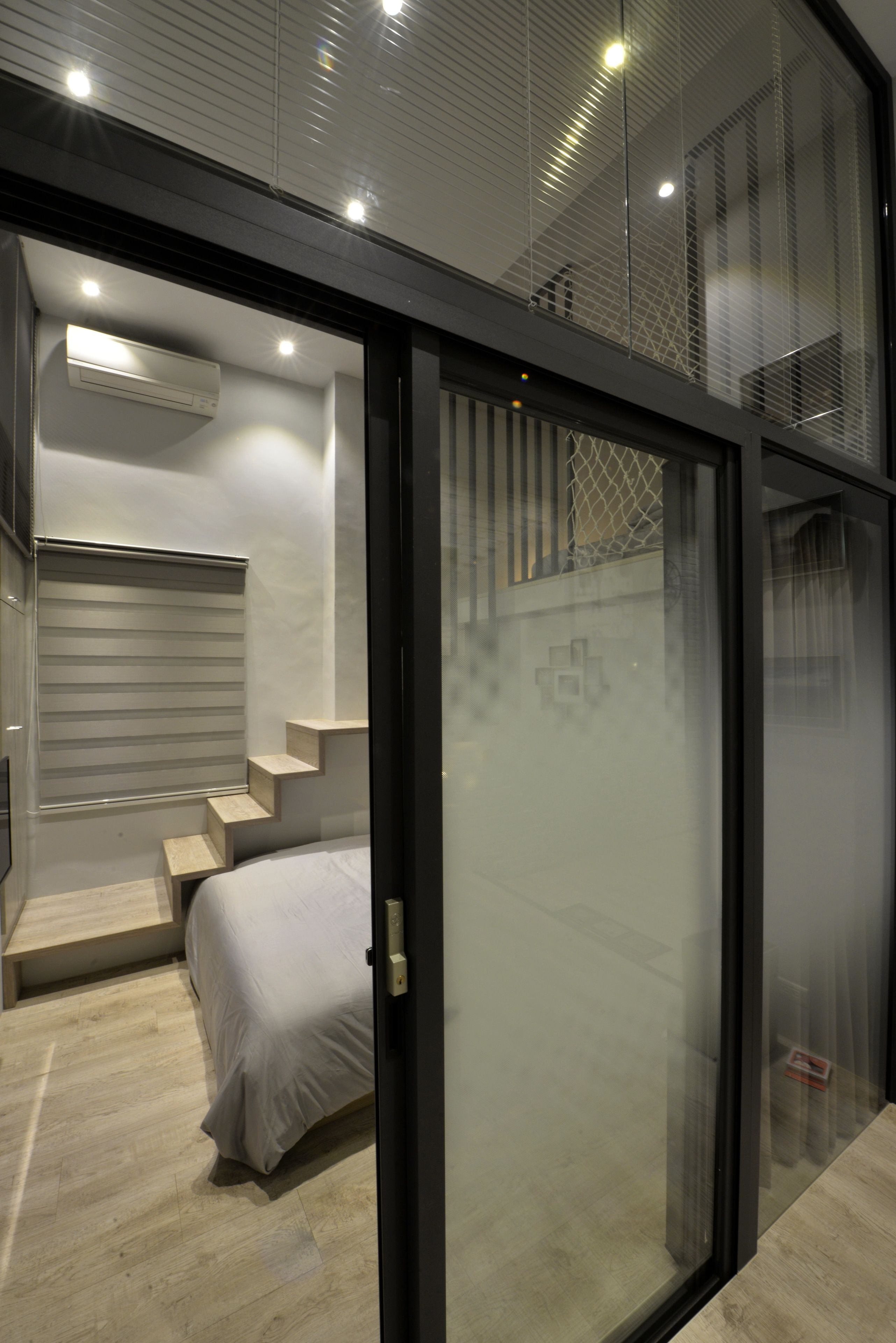 Quarto moderno com cama, um banco embutido e escada que leva a um andar superior.