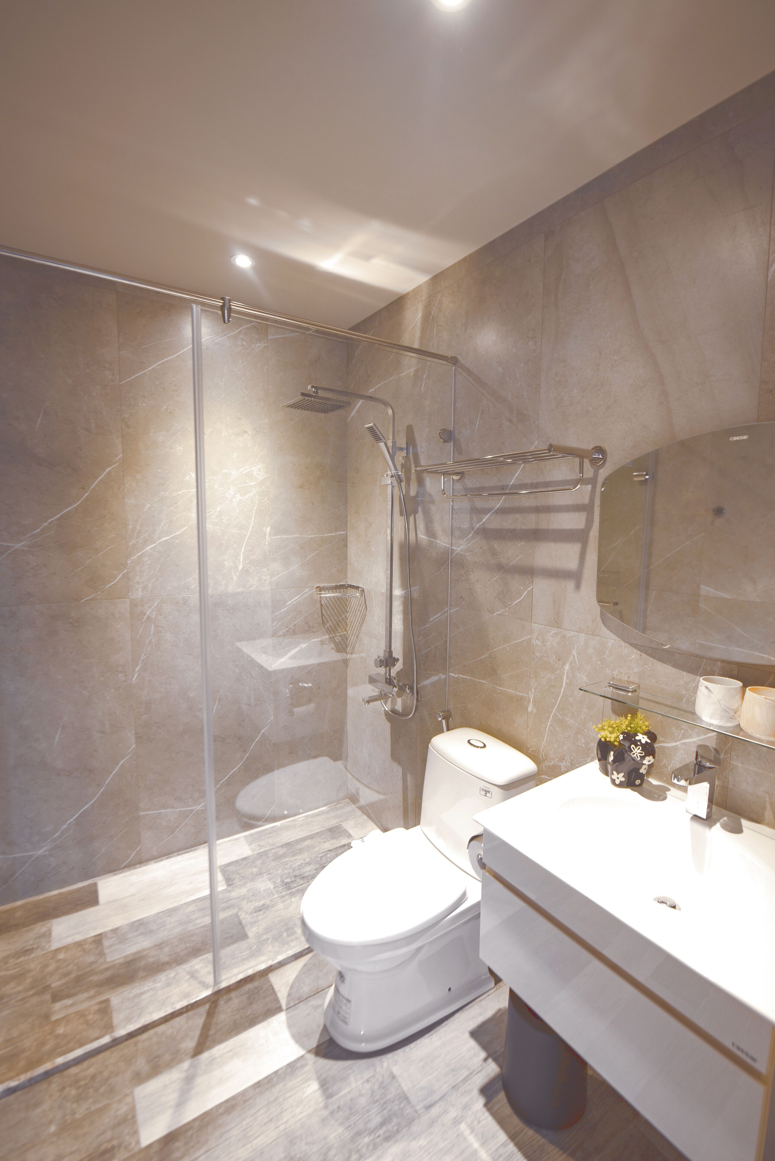 A modern bathroom with a glass-enclosed shower, a toilet, and a vanity with a mirror.