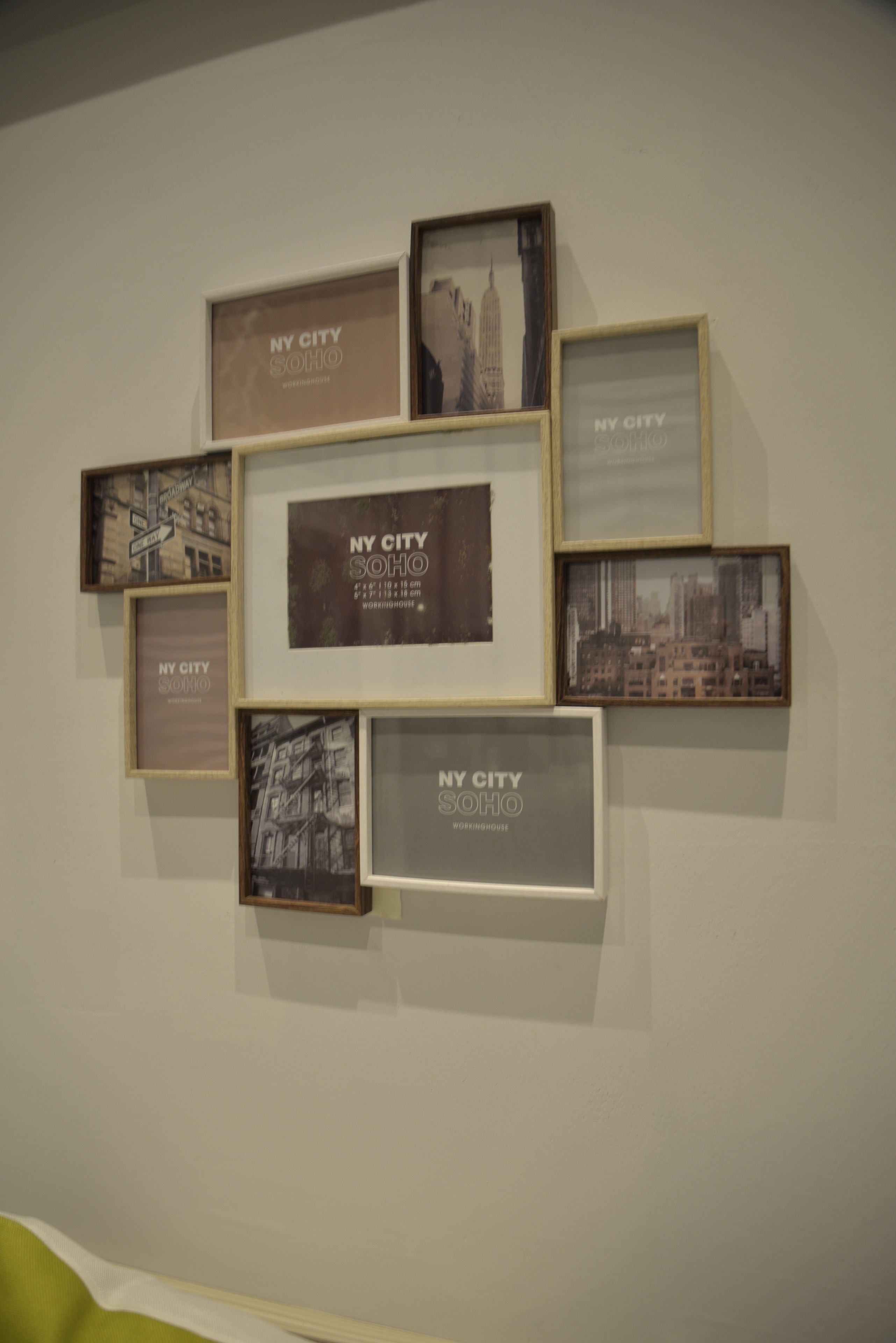 A wall with multiple framed photographs of New York City, arranged in a grid pattern.