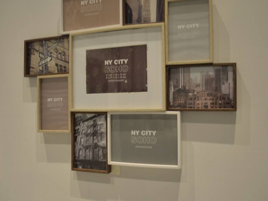 A wall with multiple framed photographs of New York City, arranged in a grid pattern.