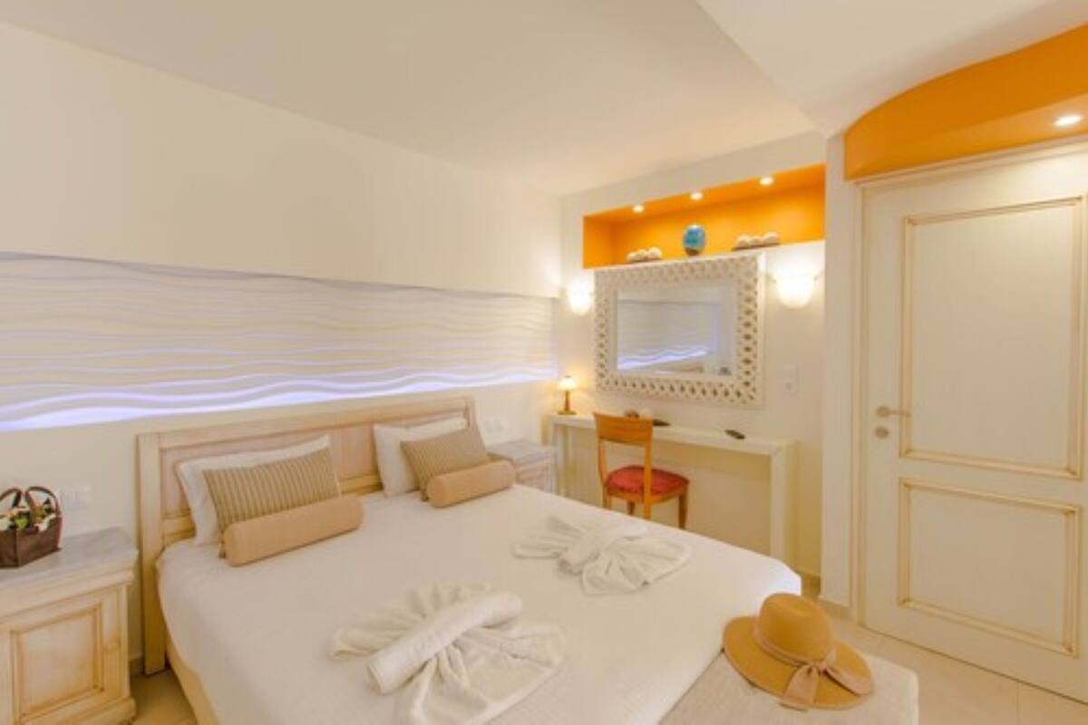 Een hotelkamer met een opgemaakt bed, een nachtkastje met een lamp, een stoel en een kledingkast.