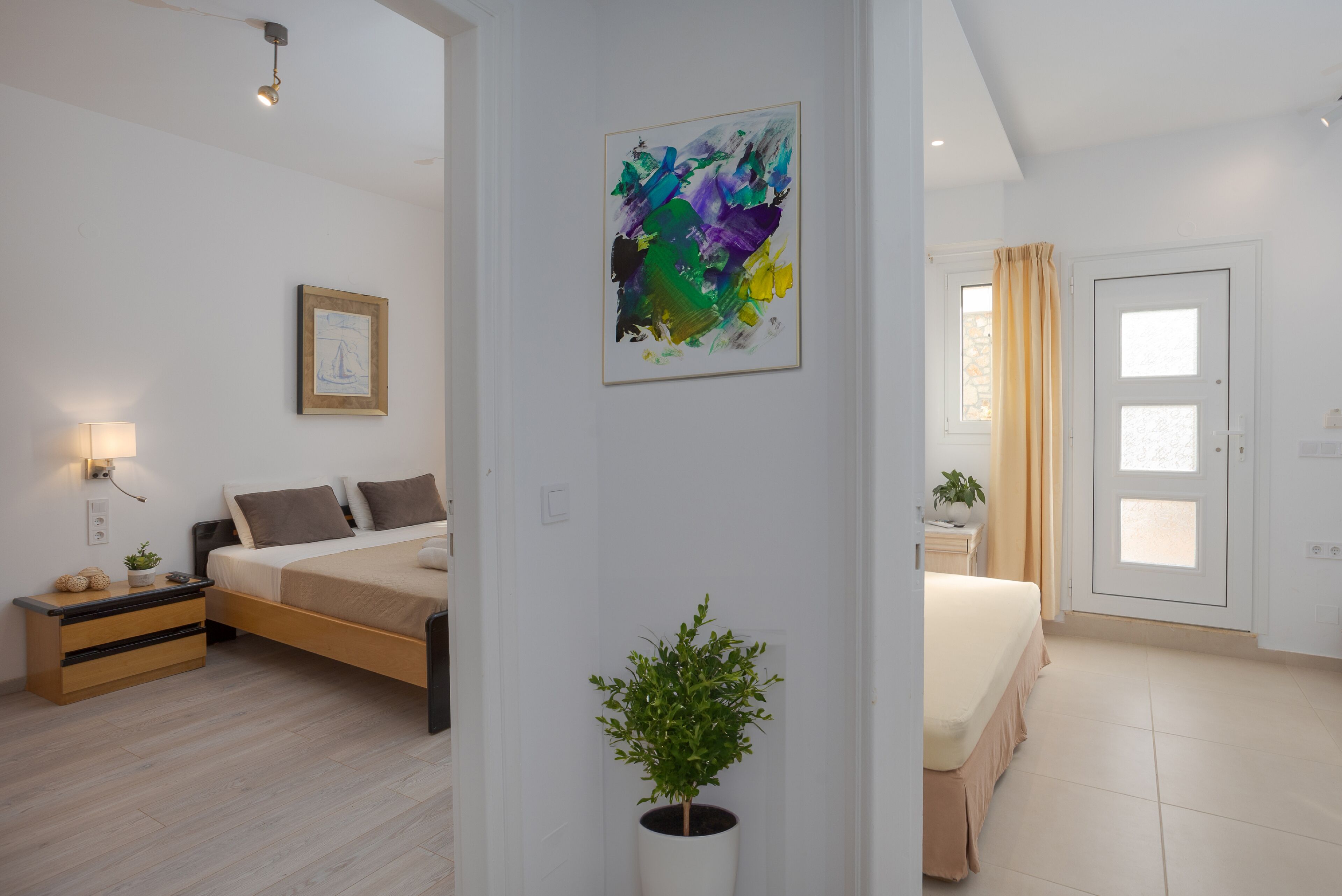 Un dormitorio moderno con cama, mesitas de noche, una planta en maceta y obras de arte en la pared.