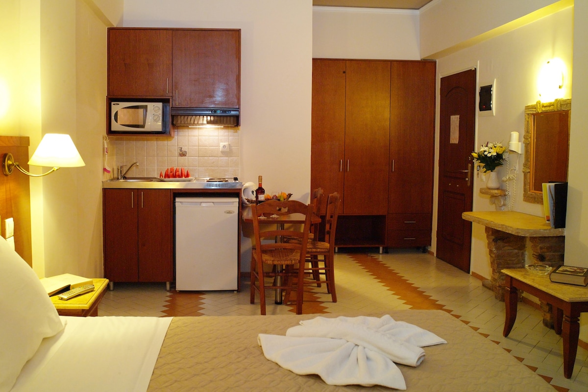 Een hotelkamer met een bed, een kitchenette, een eethoek en een badkamer.