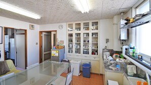 Una cocina con armarios, un refrigerador, un microondas y un ventanal.