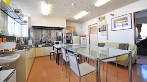 Una cocina compacta con electrodomésticos modernos, un comedor con mesa de vidrio y una sala de estar con sofá.