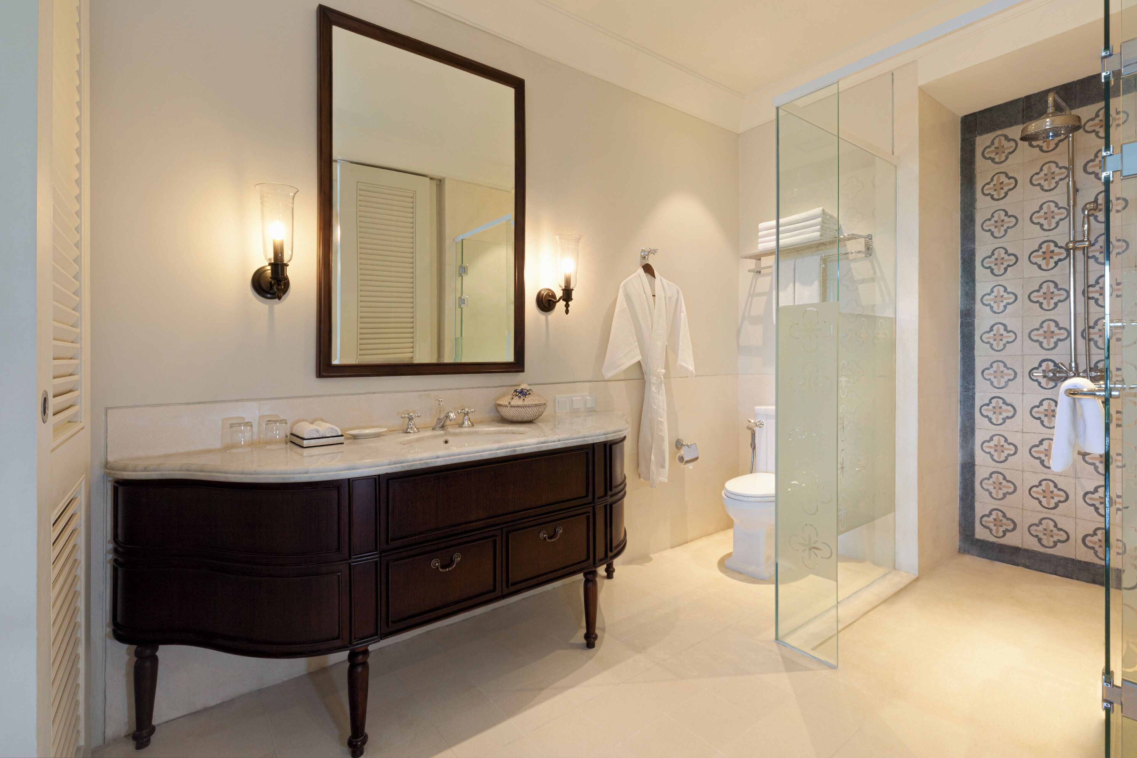 Un baño con tocador de madera oscura, un espejo grande y una cabina de ducha de vidrio.