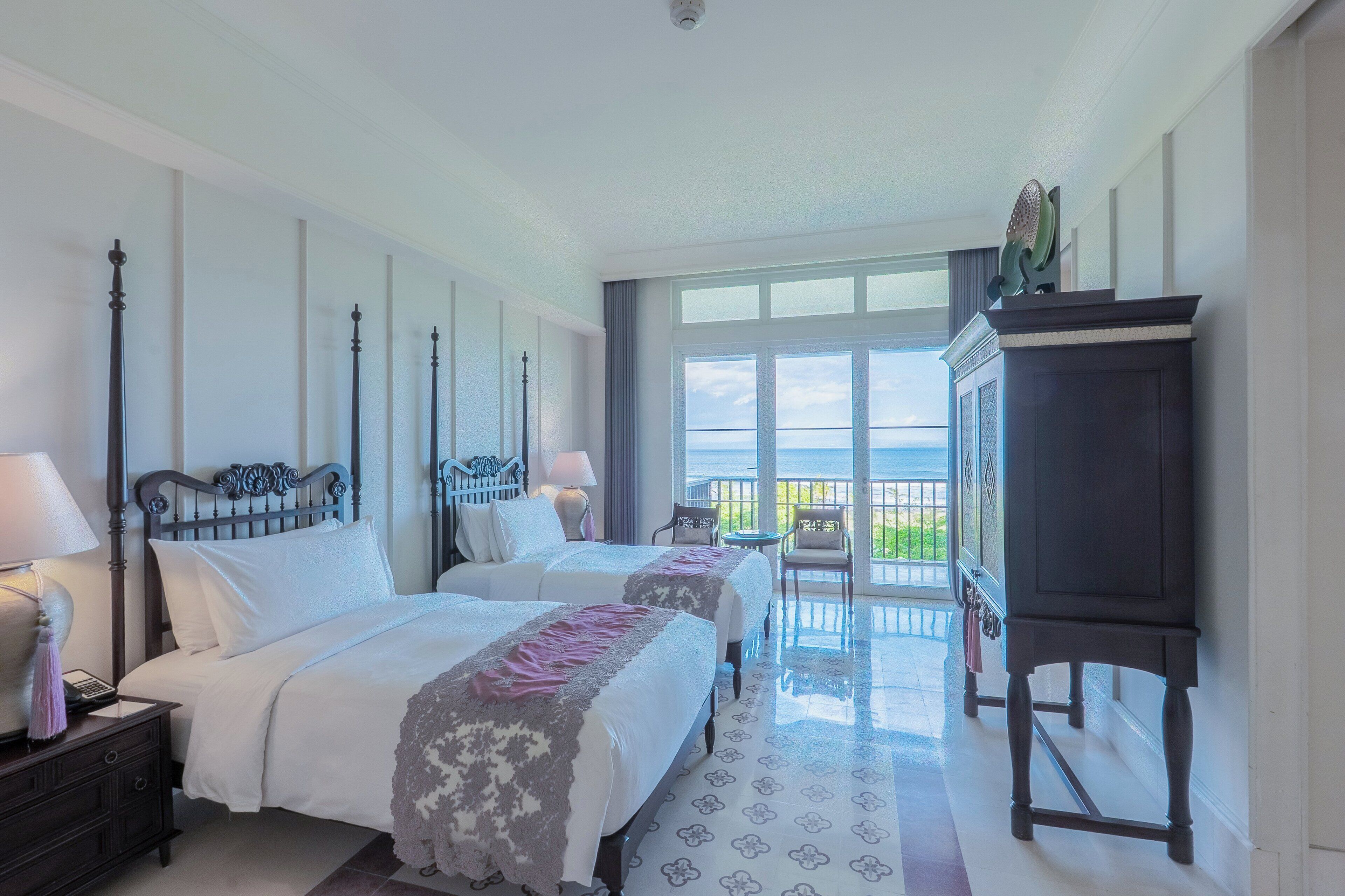A hotel room with two beds, a nightstand, a dresser, and a balcony with a view.