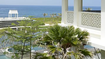 A resort with a pool, palm trees, and a view of the ocean.