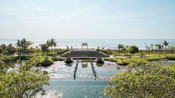 Ein Resort mit großem Pool, Palmen und Blick auf den Ozean.