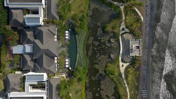 Vista aérea de una zona residencial moderna con un gran estanque, un sendero curvo y una playa.