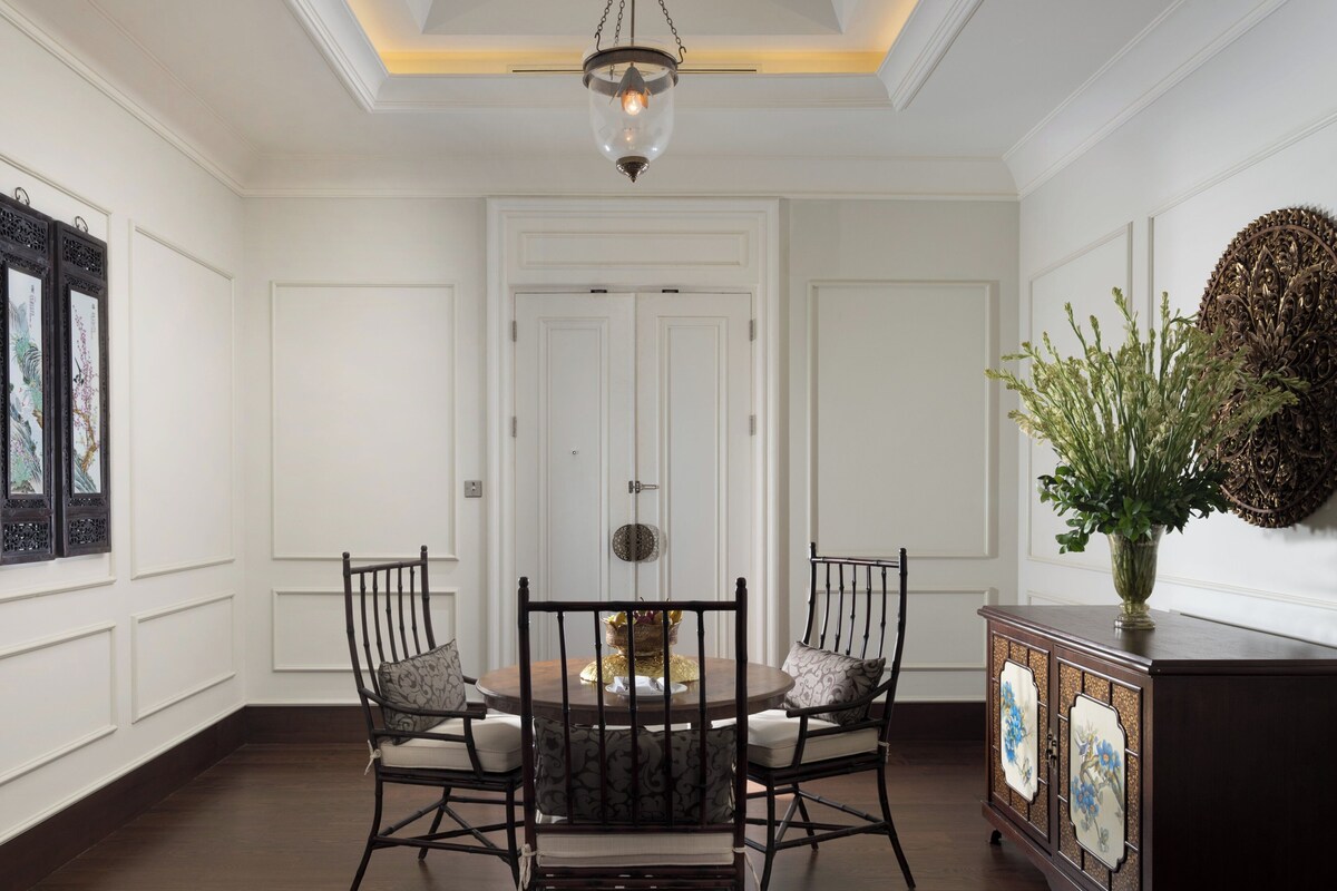 A dining area with a wooden table and chairs, a decorative vase, and a cabinet with patterned doors.