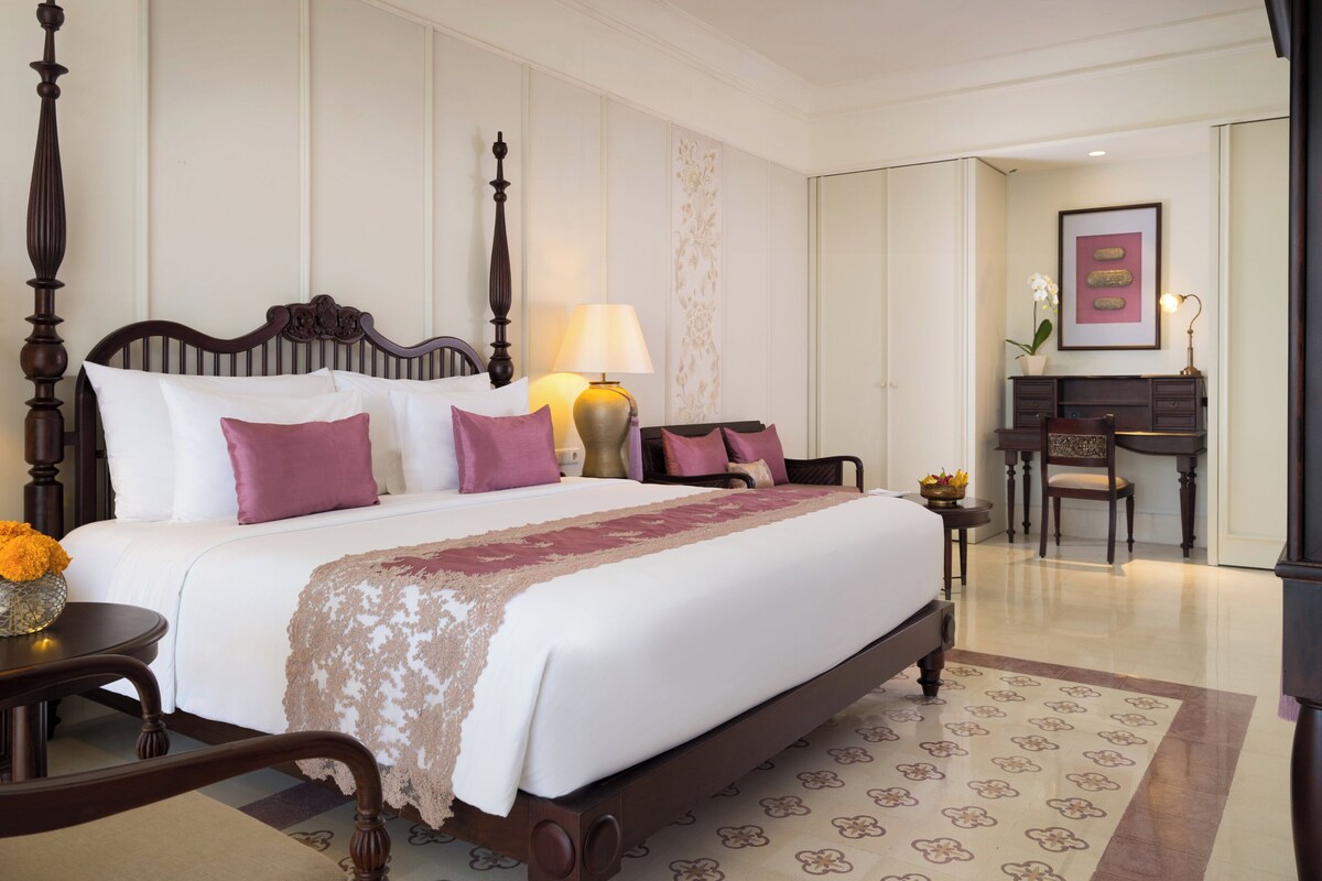 A hotel room with a four-poster bed, a desk, and a chair.