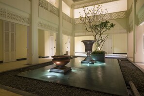 Un espacio interior amplio con una fuente central, jarrones decorativos y una planta en maceta.