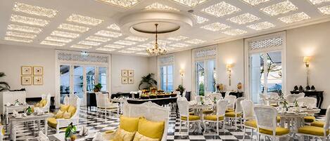A hotel lobby with a checkered floor, white furniture, and decorative ceiling panels.