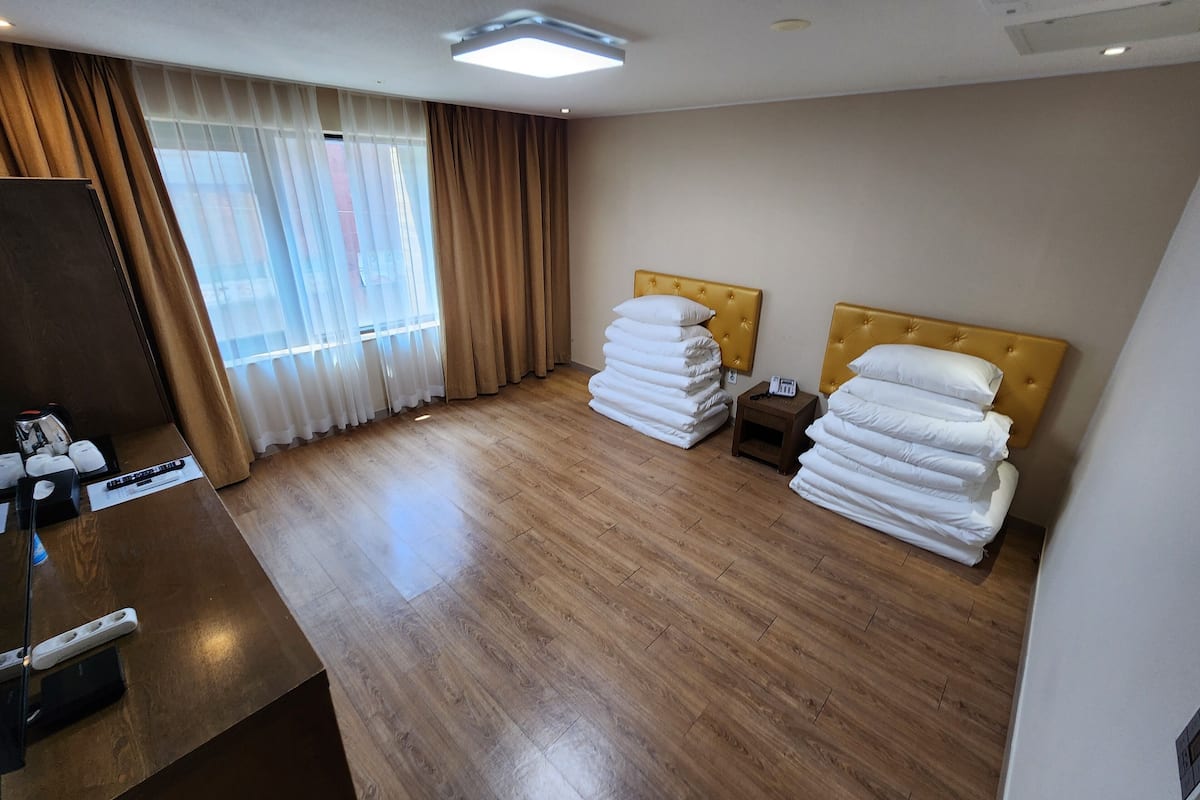 A hotel room with two beds, a desk, a telephone, and a window with curtains.