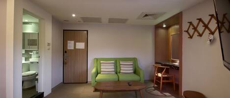 A living room with a green sofa, a wooden coffee table, and a small brown stool.