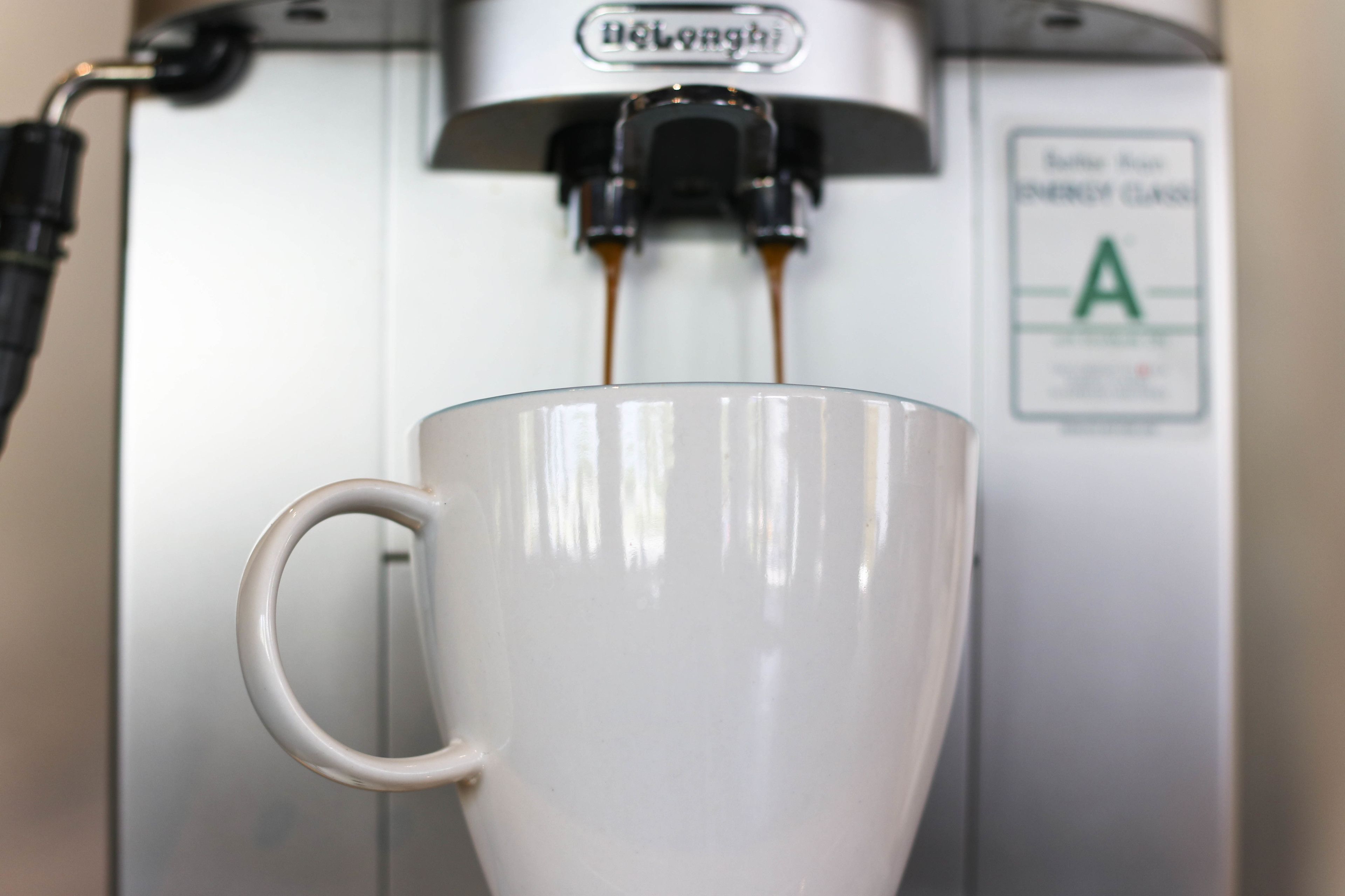 Una cafetera sirviendo café en una taza blanca.