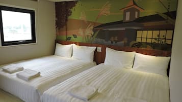A hotel room with two beds, each with white linens and towels, a window with a view of greenery, and a mural on the wall depicting a landscape with a building.