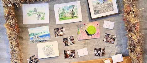 A bulletin board with various framed artworks, photographs, and notes pinned to it.