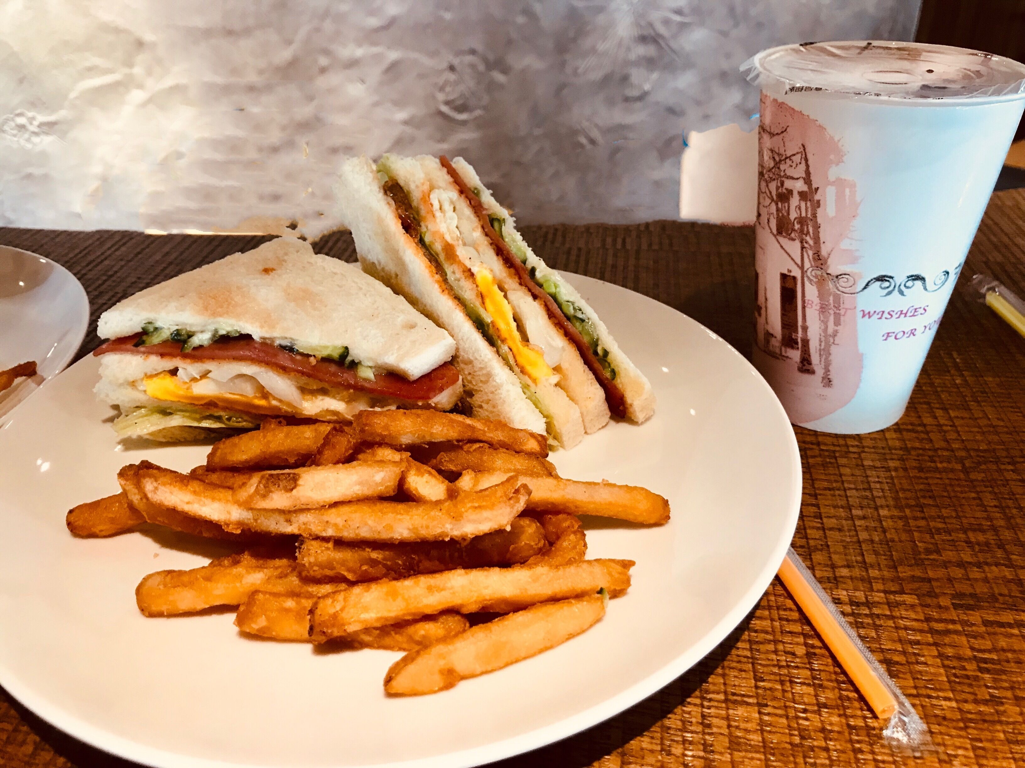 Une assiette avec un sandwich coupé en deux et une portion de frites.