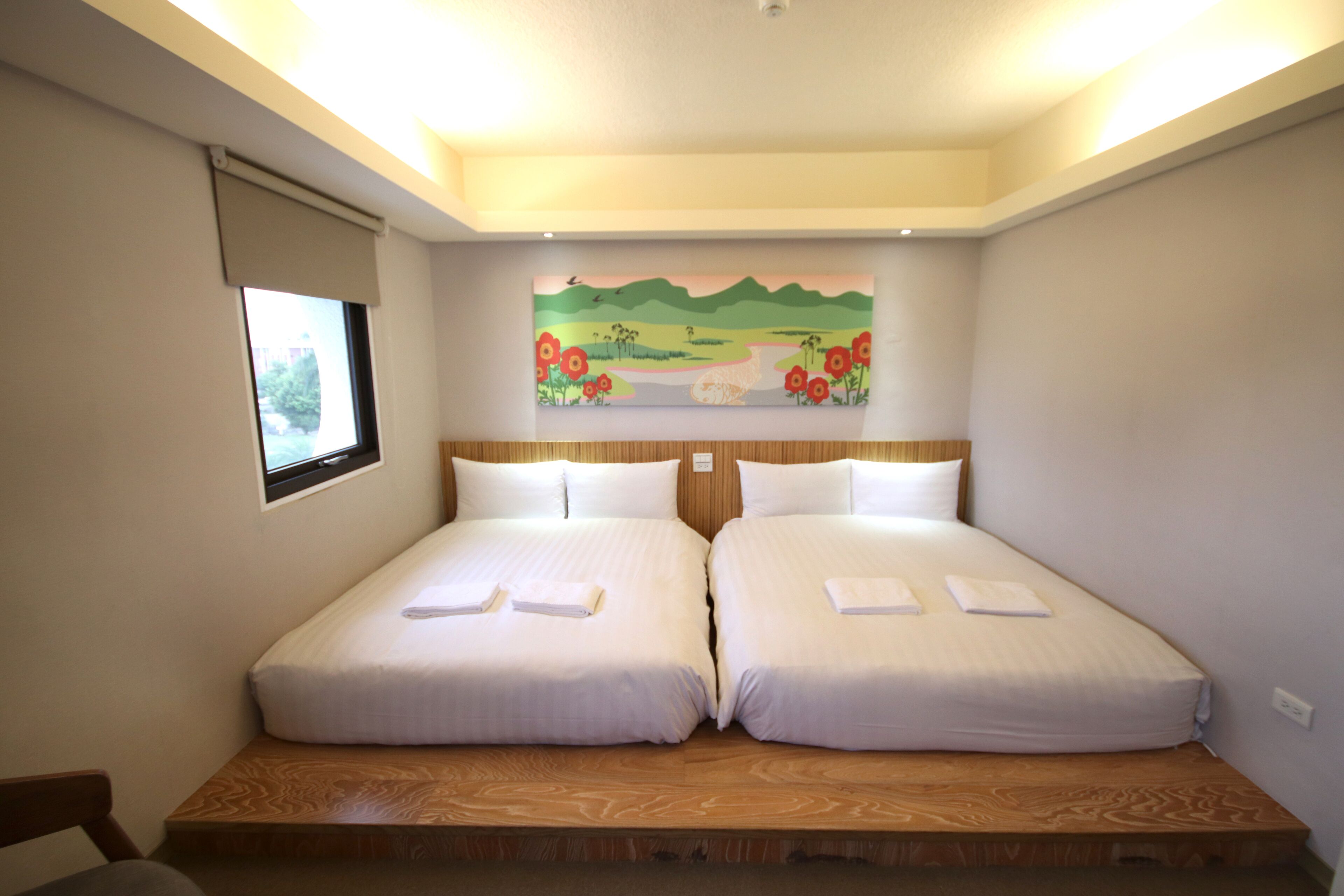 A double room with two beds, a painting on the wall, and a window with a view.
