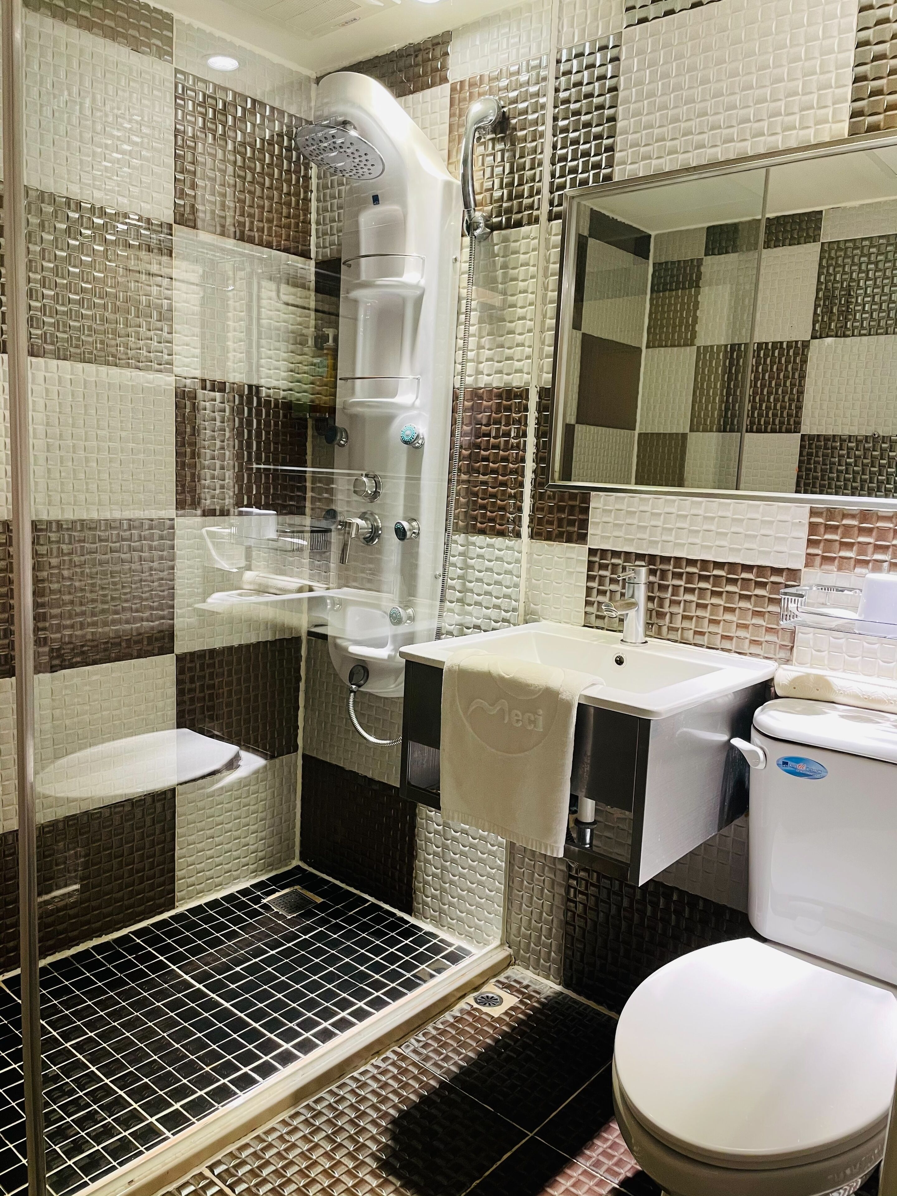 Une salle de bain équipée d’une douche, de toilettes, d’un lavabo et d’un miroir.