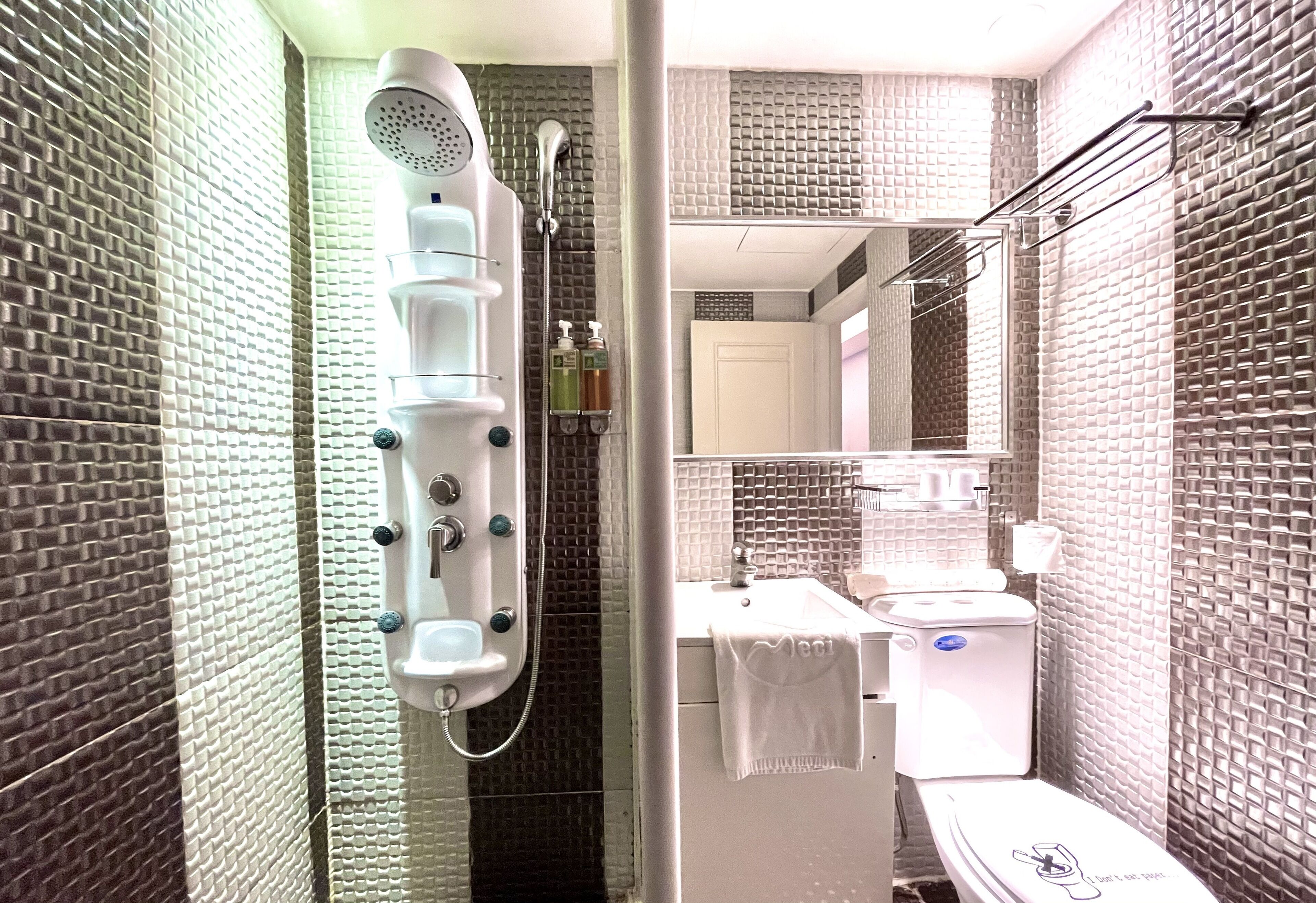 A bathroom with a shower, toilet, sink, and mirror.