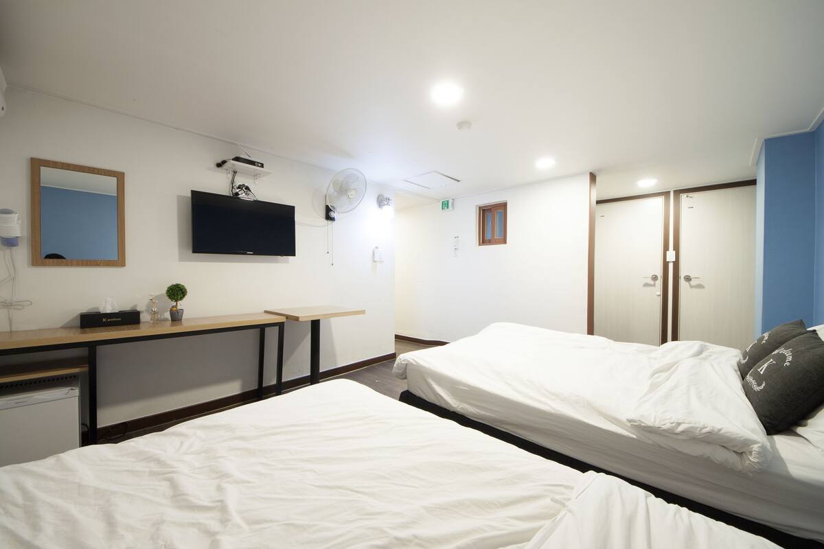 Een hotelkamer met twee bedden, een bureau, een televisie en een spiegel.