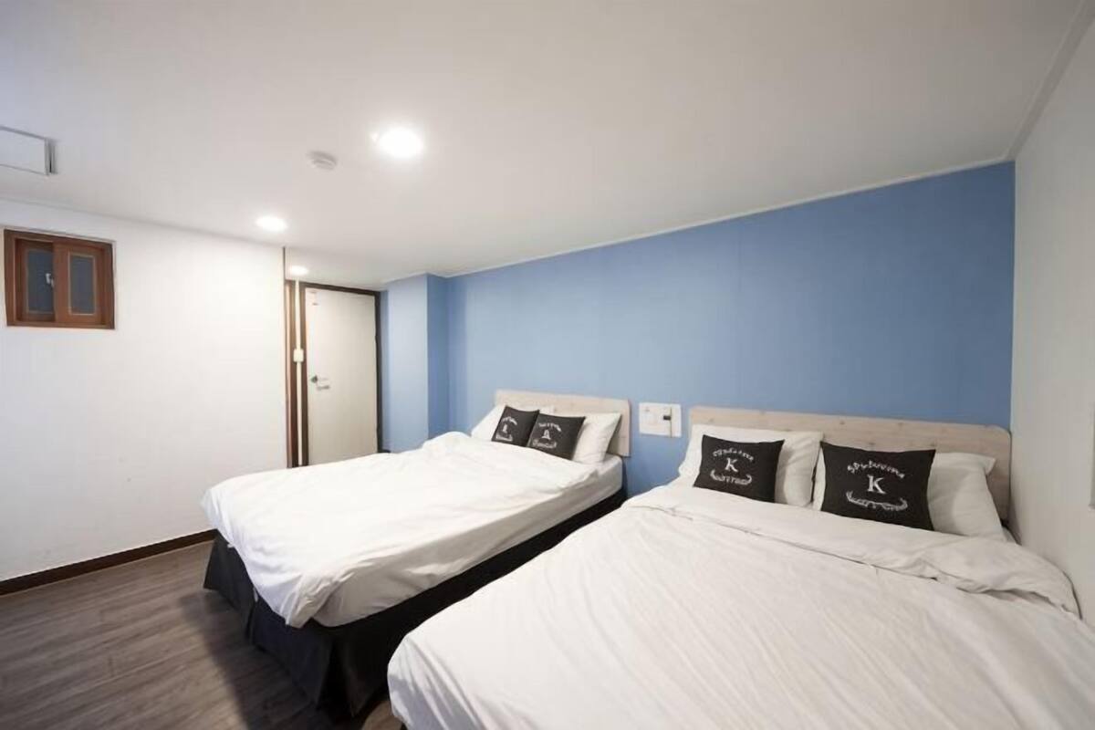 Een kamer met twee bedden, een houten deur en een blauwe wand.