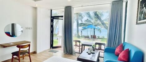 A hotel room with a bed, a desk, a chair, a blue sofa, and a large window with curtains.