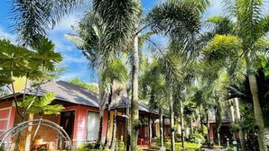 A pathway lined with palm trees and a swing chair, leading to a building with a tiled roof. - Orange Resort (Phu Quoc)