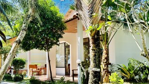 A modern building with a covered outdoor seating area, surrounded by lush tropical vegetation. - Orange Resort (Phu Quoc)