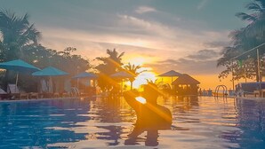 A poolside view with umbrellas and lounge chairs, a clear sky, and a sunset. - Orange Resort (Phu Quoc)