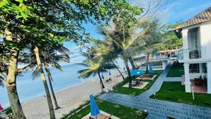 A beachfront property with a pool, lounge chairs, and a pathway leading to a building. - Orange Resort (Phu Quoc)