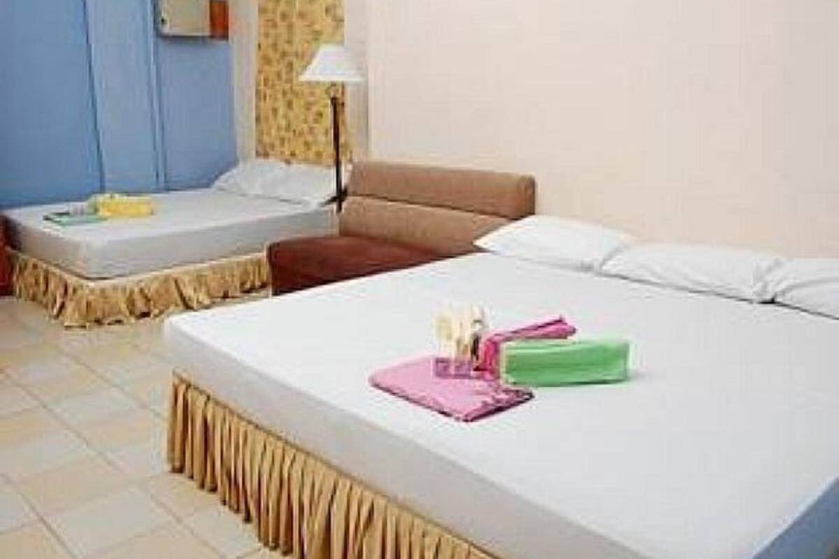 A hotel room with a bed, a chair, a small table, and a lamp.